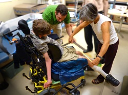 Picture of Kelly measuring legs of client in wheelchair Picture of Kelly measuring legs of client in wheelchair