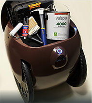 : A Gita Robot with two wheels balancing itself like a Segway. It has a cargo bin storing up to 40 lbs. of personal items, such as a hammer, a can of paint, a paintbrush, a paint roller, and a toolbox. It has three built-in cameras at the front to sense the environment, allowing it to follow a human. A single button on top of the camera with an LED light pairs it with a user.