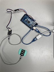The device is attached to a computer. It consists of a microcontroller, and it is connected to an analog electromyogram sensor.