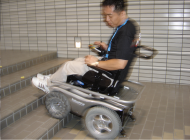 Pictures of two wheelchair users demonstrating driving with the &ldquo;Patrafour&rdquo; over  2inch obstacles-one obstacle is a step and the other obstacle  is a piece of wood