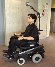 This image provides an external view of the electric wheelchair prototype. The positioning of the SOS above and forward of the user&rsquo;s head offers the following advantages: (1) a wide observation range can be provided, without blind spots in the electric wheelchair&rsquo;s surroundings; (2) there is no hindrance to getting in and out of the wheelchair; and (3) the SOS is positioned at approximately body height, thereby providing clearance in normal living spaces.